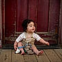 Lukah is registered to the contest to win money with this photo: baby, bracelet, child, clothing, curly_hair, cute, doorframe, expression, face, happy, infant, outdoor, person, playful, red_door, sitting, smiling, toy, weathered, wooden_floor