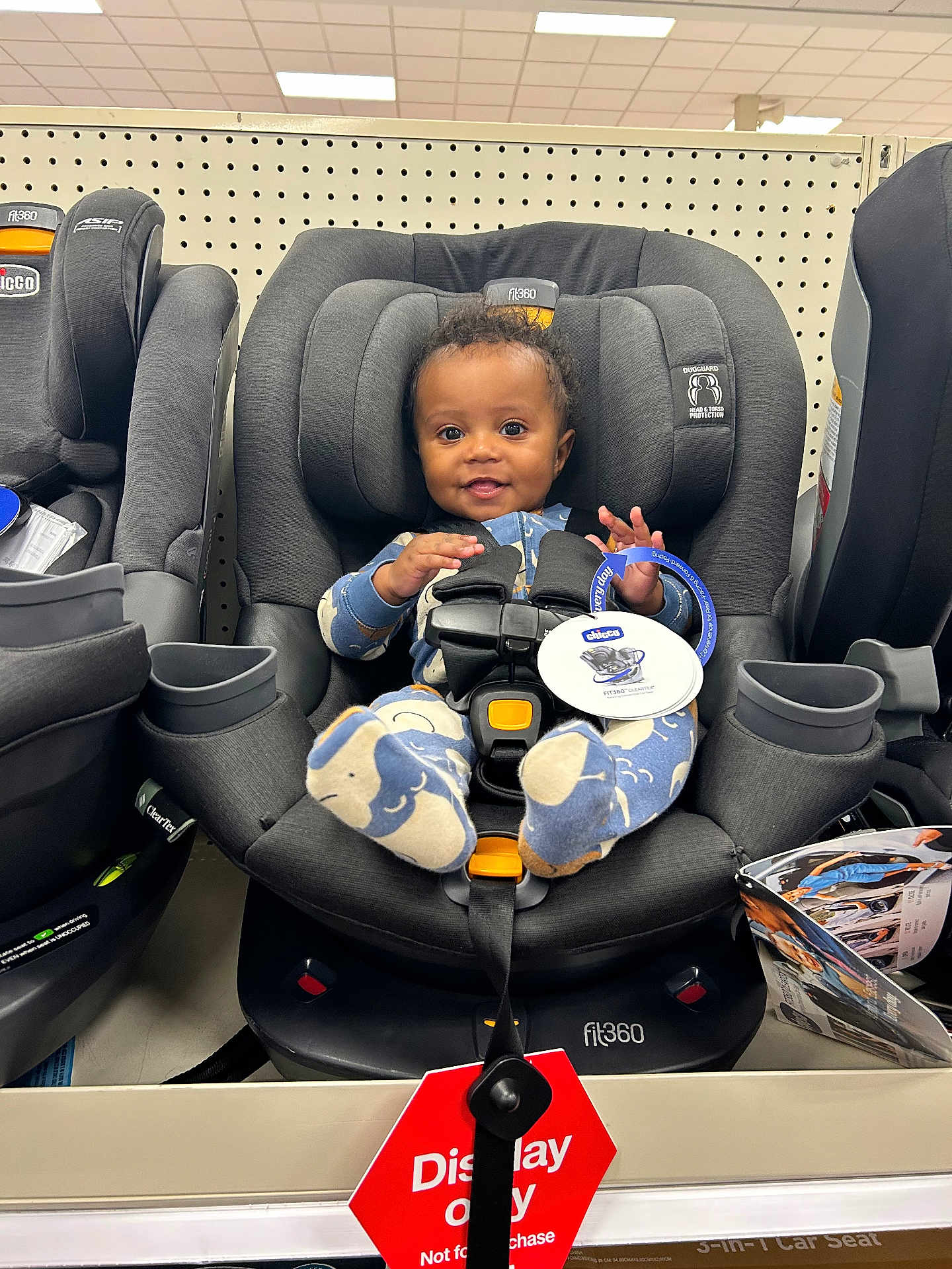 Messiah joined the competition — help win amazing prizes! baby, car_seat, child, store, display, retail, product, smile, clothing, footwear, shelf, indoor, person, head, seat_belt, tag, happy, toy, shopping, infant