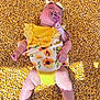baby, infant, pacifier, yellow_clothing, sunflower_pattern, corn_kernels, lying_down, sleeping, headband, barefoot, sunlight, shadow, cute, child, outdoor, summer, soft_skin, adorable, resting, bright_colors