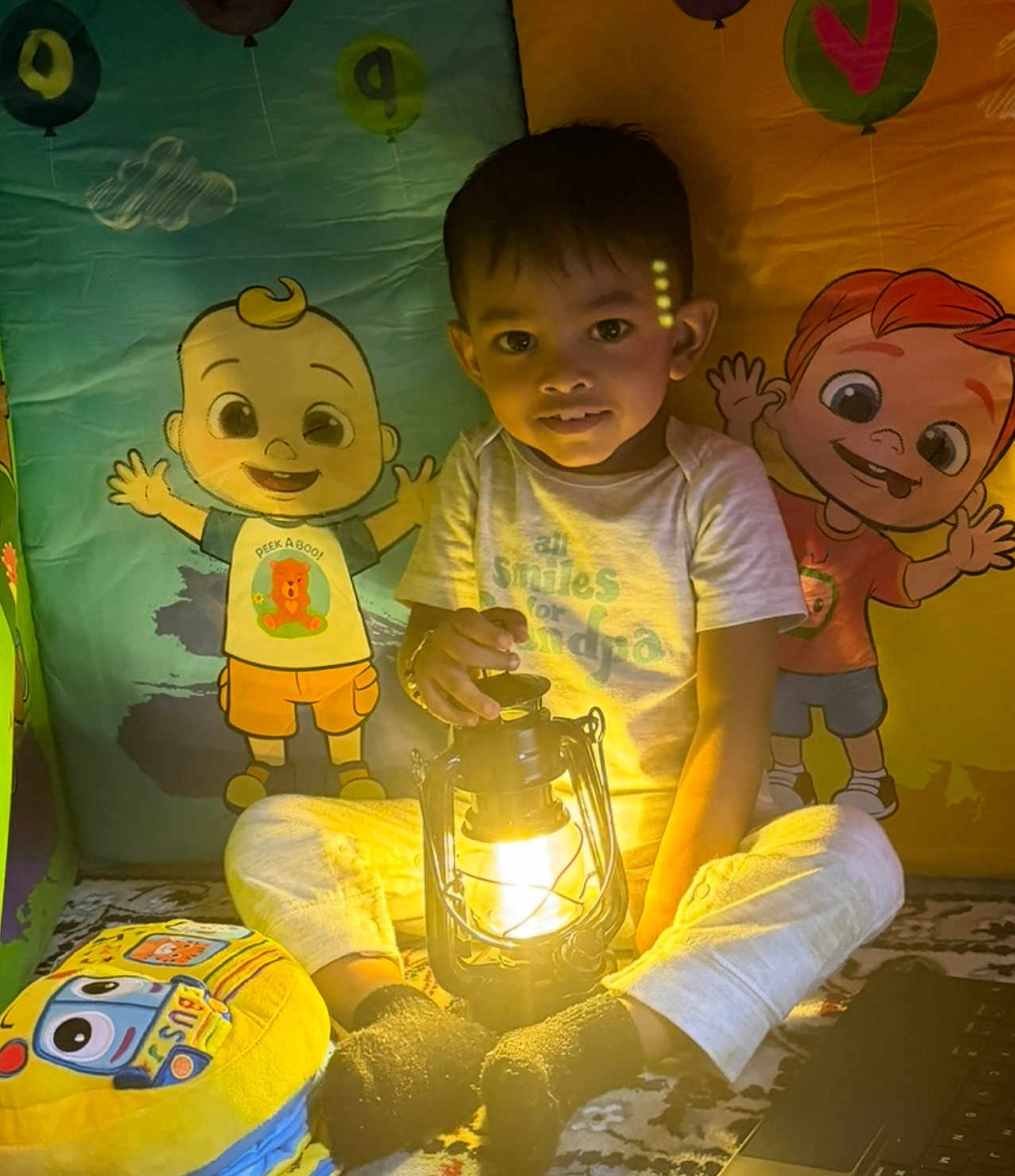 Jayden joined the competition — help win amazing prizes! child, lantern, light, indoor, cartoon, illustration, playmat, toy, socks, pants, tshirt, smile, face, kid, colorful, background, playroom, cozy, warm_light, sitting
