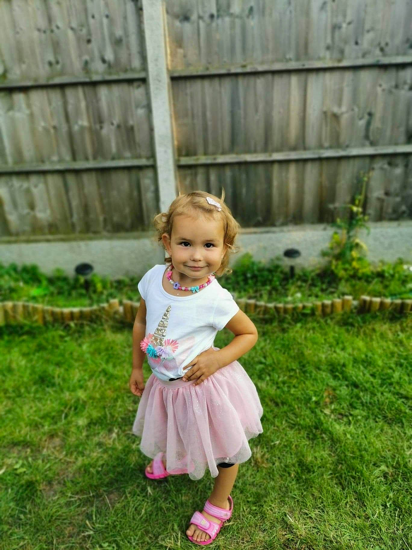 Karina is registered to the contest to win money with this photo: baby, baby_toddler_clothing, child, fence, fun, grass, grassland, hair, happy, joy, landscape, lawn, leisure, meadow, people_in_nature, person, plant, recreation, sandal, sitting