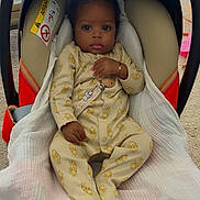 Chayden a rejoint le concours — aidez-le/la à gagner de superbes lots ! baby, child, car_seat, blanket, onesie, yellow_clothing, indoor, carrying_handle, infant, cute, face, person, portrait, seated, carpet, bracelet, pacifier_clip, expression, looking, soft