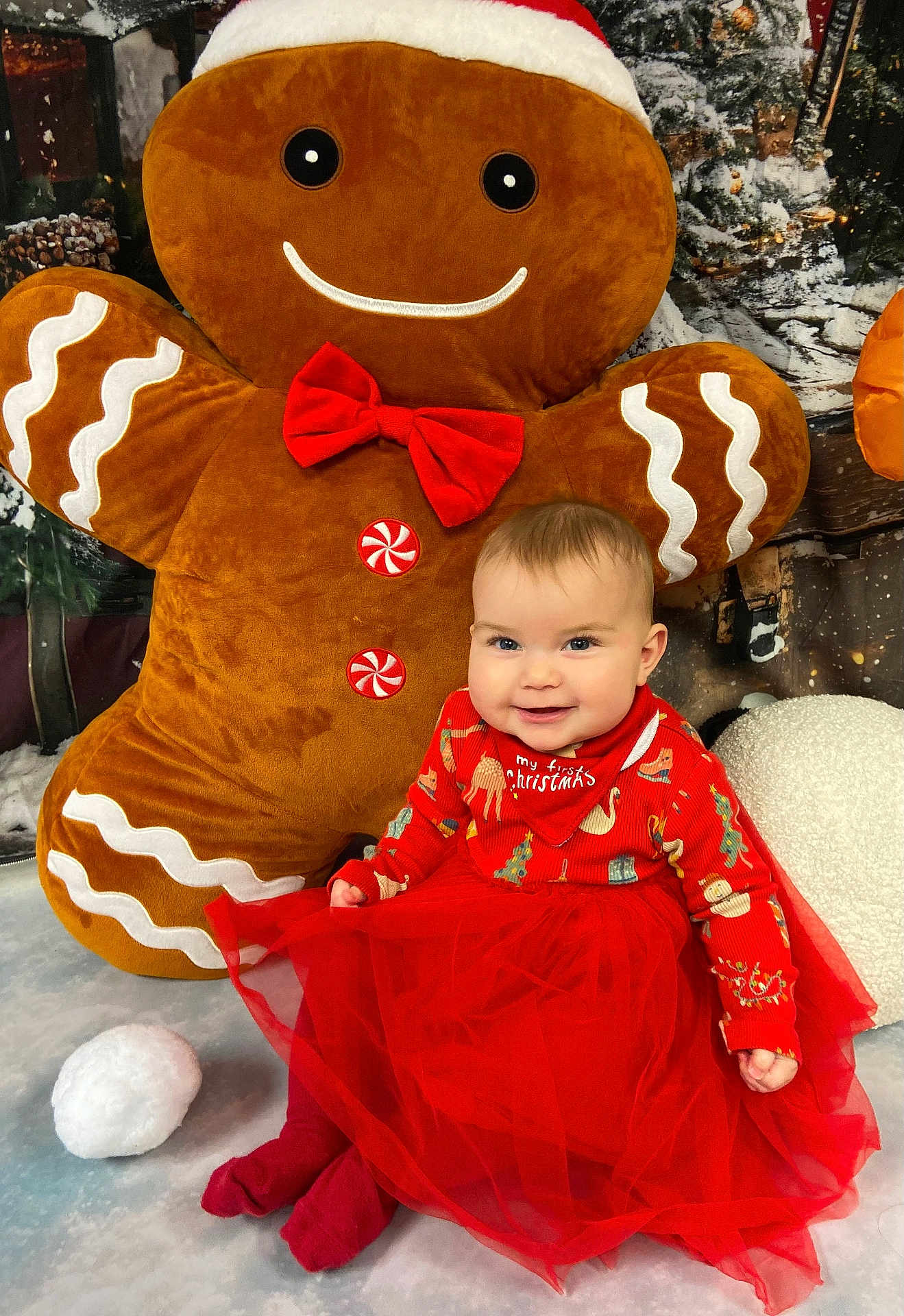 Araya joined the competition — help win amazing prizes! baby, child, tutu, red_clothing, gingerbread_man, plush_toy, holiday, christmas, festive, smile, winter, snow, background, sitting, cute, indoor, toy, red_bow, decorations, happy