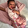 baby, smiling, pink_clothing, blanket, pacifier, curly_hair, infant, cute, happy, soft_texture, lying_down, indoor, child, cozy, headband, playful, sunlight, person, toddler, closeup