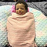 Kehlani is registered to the contest to win money with this photo: baby, infant, smile, blanket, cushion, bed, bedding, face, person, indoor, happy, cute, wrapped, pink, pastel, texture, cozy, child, tongue, curly_hair