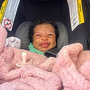 Kehlani joined the competition — help win amazing prizes! baby, infant, car_seat, blanket, pink, pacifier, smiling, face, curly_hair, child, seatbelt, safety, cozy, indoors, cute, person, young_child, car_accessory, expression, wrapped