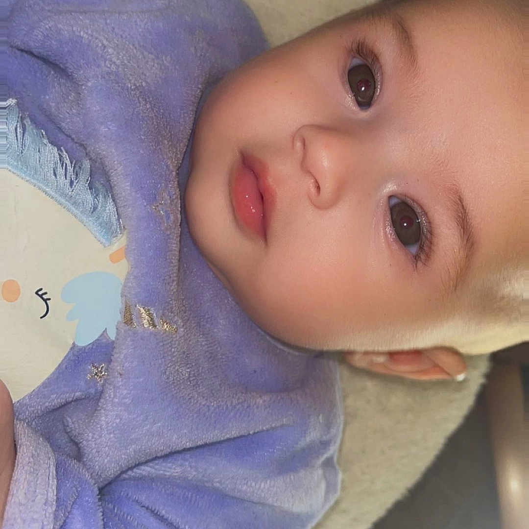 Alma a rejoint le concours — aidez-le/la à gagner de superbes lots ! baby, child, face, portrait, close_up, blanket, purple, soft_texture, cute, infant, young_child, indoors, cozy, expression, lying_down, skin, eyelashes, clothing, head, person