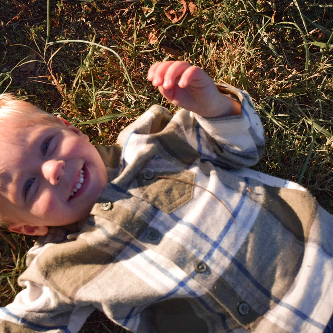 Wyatt is registered to the contest to win money with this photo: baby, bodypart, clothing, coat, face, finger, grass, hand, happy, head, jacket, knitwear, pants, person, photography, plant, portrait, smile, sweater, sweatshirt