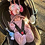 baby, car_seat, plush_toy, pink_onesie, outdoor, sunlight, infant, toy, baby_clothing, child, seatbelt, stroller, cute, soft_toy, hooded_onesie, expression, animal_ears, safety_harness, walking_path, daylight