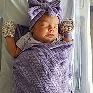Lilly is registered to the contest to win money with this photo: newborn, baby, sleeping, purple_blanket, headwrap, mittens, hospital_bassinet, infant, peaceful, swaddled, face, person, sleep, soft_light, closeup, cozy, cute, child, wrapped, resting