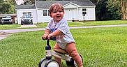 Rylie is registered to the contest to win money with this photo: baby, child, daylight, fun, grass, greenery, happy, house, lawn, nature, outdoor, person, play, smiling, summer, toddler, toy, tree, tricycle, vehicle