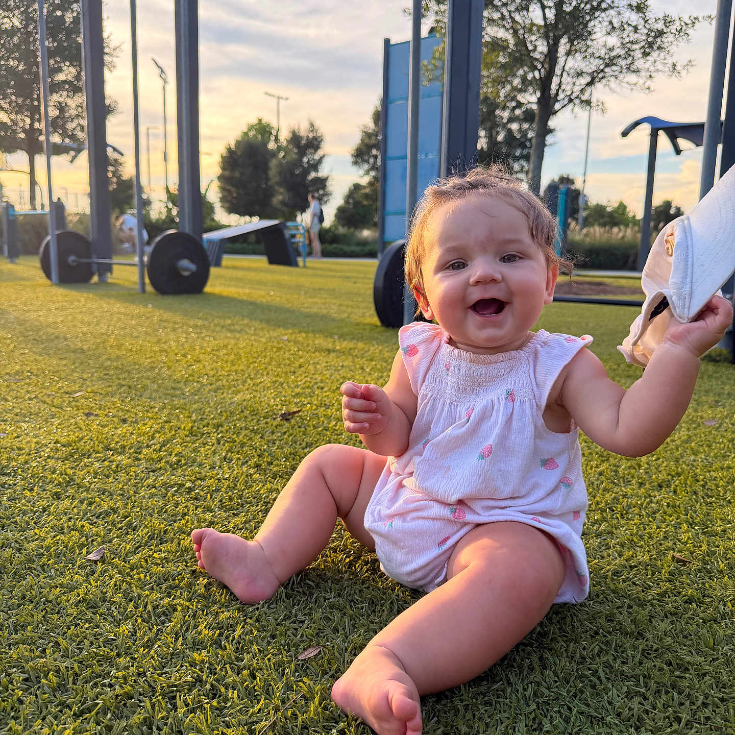 Rylie joined the competition — help win amazing prizes! baby, child, grass, playground, smiling, outdoor, sunset, hat, sitting, trees, exercise_equipment, happy, person, nature, sunlight, feet, clothing, park, daylight, cute