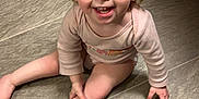 Layla is registered to the contest to win money with this photo: baby, barefoot, child, curly_hair, cute, face, floor, happy, indoor, onesie, person, pink_nail_polish, playful, sitting, skin, small_child, smiling, tile_floor, toddler, young