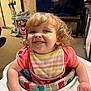 baby_walker, bib, carpet, child, curly_hair, cute, face, furniture, hand, happy, home, indoor, living_room, person, pink_shirt, playtime, smile, television, toddler, toy