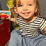 blue_skirt, carpet, child, colorful, container, curly_hair, cute, earrings, floor, happy, indoor, person, playtime, portrait, smiling, striped_shirt, toddler, toy, wall, young_child