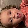 Layla is registered to the contest to win money with this photo: baby, child, close_up, curly_hair, cute, earrings, expression, face, happy, headshot, indoor, lying_down, person, pink_clothing, playful, polka_dot, portrait, smile, tongue, young_child