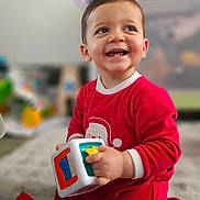 Andrea a rejoint le concours — aidez-le/la à gagner de superbes lots ! toddler, child, smiling, red_onesie, toy, indoor, carpet, playing, happy, baby, cute, kneeling, young_child, colorful_toy, face, person, home, floor, expression, clothing