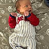 Emerson is registered to the contest to win money with this photo: baby, bed, blanket, clothing, cute, face, fist, floral, head, indoor, infant, lying_down, newborn, onesie, pattern, person, portrait, skin, sleepwear, soft