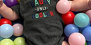 Zachary is registered to the contest to win money with this photo: baby, infant, child, onesie, plastic_balls, ball_pit, colorful, play_area, cute, portrait, indoor, clothing, person, skin, face, legs, arms, expression, sitting, soft_lighting