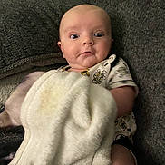 Zachary joined the competition — help win amazing prizes! baby, blanket, couch, child, expression, face, furniture, indoor, infant, person, plush, portrait, sitting, surprised, toddler, white_blanket, gray_couch, cute, young_child, cozy