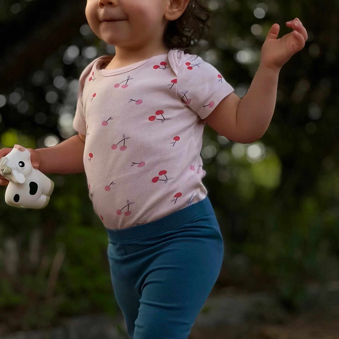 Sofya a rejoint le concours — aidez-le/la à gagner de superbes lots ! toddler, child, outdoor, toy, cow, shirt, cherry_pattern, pants, blue_pants, bear_patch, shoes, walking, nature, trees, bokeh, person, cute, confident, smiling, young_child
