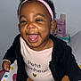 toddler, smiling, pink_bow, headband, baby, happy, child, black_jacket, brown_pants, indoor, person, cute, infant, joyful, sitting, face, closeup, clothing, expression, playful