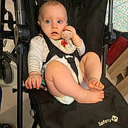 Louve is registered to the contest to win money with this photo: baby, stroller, pacifier, bib, diaper, infant, child, sitting, black, clothing, foot, hand, face, blue_eyes, indoor, safety_1st, expression, curious, person, furniture