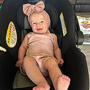 Alyona is registered to the contest to win money with this photo: baby, infant, car_seat, pink_outfit, headband, bow, smiling, happy, indoor, furniture, couch, blanket, person, child, feet, cute, seated, comfort, portrait, clothing