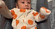 Ace'Lynn is registered to the contest to win money with this photo: baby, baby_seat, child, clothing, cozy, cushion, cute, face, gray, hands, indoor, infant, looking, onesie, portrait, pumpkin_pattern, seatbelt, soft, warning_label, young_child