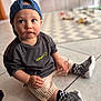 toddler, child, cap, blue_cap, striped_shorts, checkered_socks, sneakers, floor, tile_floor, indoor, curious, sitting, casual_clothing, portrait, young_child, person, cute, baby, fashion, blurry_background