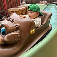 César a rejoint le concours — aidez-le/la à gagner de superbes lots ! toddler, child, green_cap, boat_ride, water_ride, amusement_park, brown_boat, outdoor, curious, water, playful, fun, young_child, casual_clothing, fence, wooden_furniture, summer, daytime, family_fun, portrait