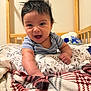 baby, smiling, happy, infant, face, arm, blanket, pillow, bed, crib, wooden_frame, clothing, striped_shirt, indoor, expression, hair, person, child, cute, cozy