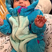 Luca is registered to the contest to win money with this photo: baby, child, onesie, blue, purple, hood, fluffy, soft, bed, crib, hand, face, expression, indoor, sleepwear, cute, infant, portrait, smile, cozy