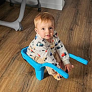 Tommy a rejoint le concours — aidez-le/la à gagner de superbes lots ! toddler, child, blue_chair, sitting, wooden_floor, sweatshirt, trucks, beige_pants, indoor, flooring, curious, looking_at_camera, small_chair, plastic_chair, light_brown_hair, long_sleeves, casual_clothing, baby, person, home