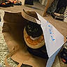 cat, black_cat, paper_bag, orange_slice_collar, indoor, carpet, floor, curious, pet, animal, cozy, room, home, playful, hideout, fur, whiskers, eyes, cute, domestic_cat