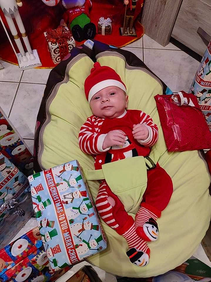 Manoa participe au concours pour gagner de l'argent avec cette photo : baby, baby_products, baby_toddler_clothing, carmine, child, christmas, christmas_eve, comfort, event, fictional_character, headwear, holiday, lap, linens, person, product, room, santa_claus, sitting, sock