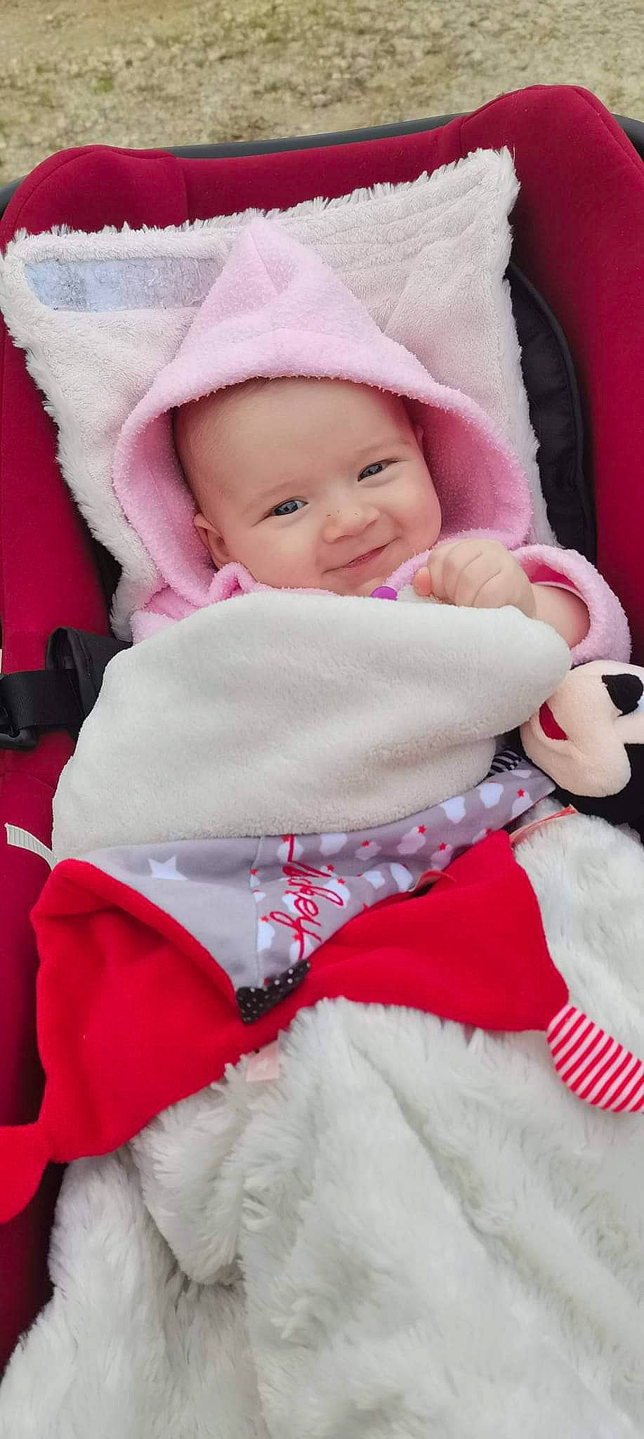 Juliette participe au concours pour gagner de l'argent avec cette photo : baby, baby_products, baby_toddler_clothing, cap, cheek, child, comfort, facial_expression, happy, headwear, lip, magenta, outerwear, person, pink, sitting, skin, sleeve, smile, textile