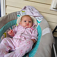Londyn joined the competition — help win amazing prizes! baby, infant, child, sitting, portrait, wide_eyes, floral_clothing, pink_outfit, onesie, padded_seat, baby_bouncer, blanket, cushion, outdoor, porch, wood_siding, head, face, adorable, photography