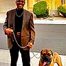 Kaytaff joined the competition — help win amazing prizes! man, dog, leash, sidewalk, house, suburban, smiling, brown_blazer, black_pants, tree, bush, road, sunlight, happy_dog, tongue_out, chain_leash, shoes, glasses, outdoor, residential_area