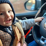 Edgar a rejoint le concours — aidez-le/la à gagner de superbes lots ! toddler, child, smiling, hat, knit_hat, car_interior, steering_wheel, clothing, hand, person, portrait, happy, cozy, seat, window, blurred_background, warm_clothing, indoor, face, baby