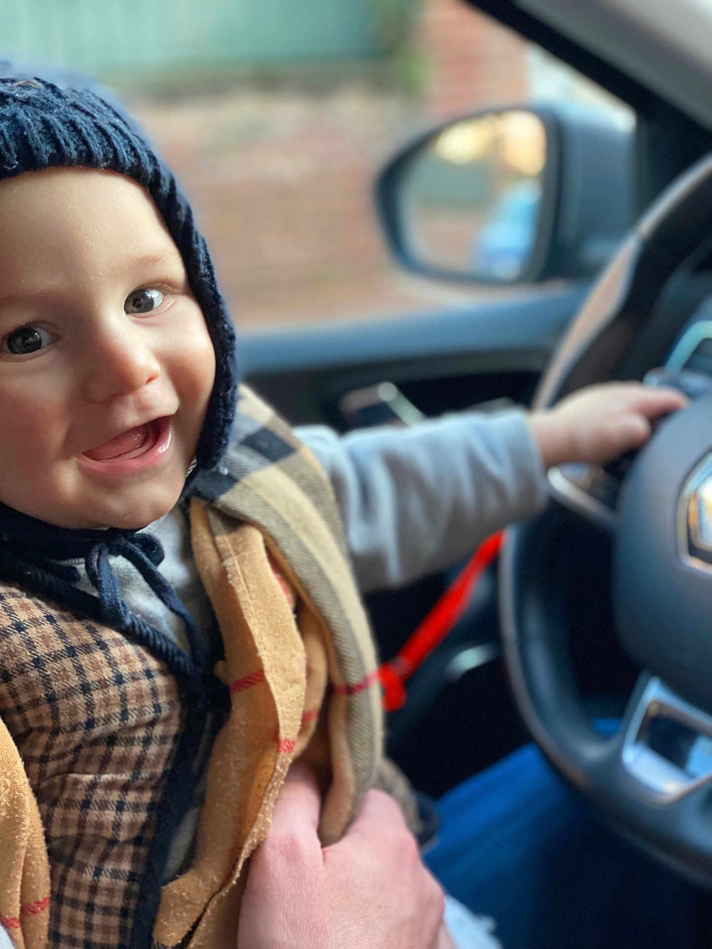 Edgar a rejoint le concours — aidez-le/la à gagner de superbes lots ! toddler, child, smiling, hat, knit_hat, car_interior, steering_wheel, clothing, hand, person, portrait, happy, cozy, seat, window, blurred_background, warm_clothing, indoor, face, baby