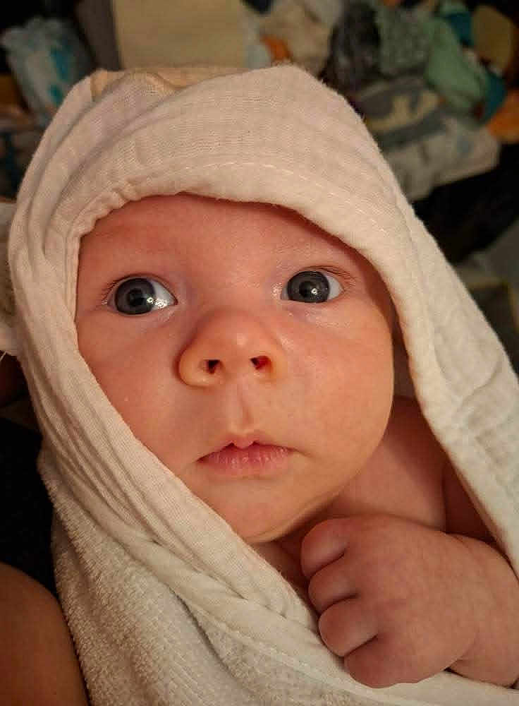 Brody is registered to the contest to win money with this photo: baby, infant, towel, face, eyes, skin, hand, newborn, portrait, closeup, cute, wrapped, soft, expression, curious, child, indoors, person, head, blanket