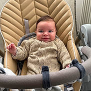 Imran participe au concours pour gagner de l'argent avec cette photo : baby, infant, baby_bouncer, knit_sweater, smiling, face, eyes, hands, plush_toy, toy_bar, seat, padded_seat, beige, indoor, parenting, cute, portrait, closeup, soft_lighting, cotton