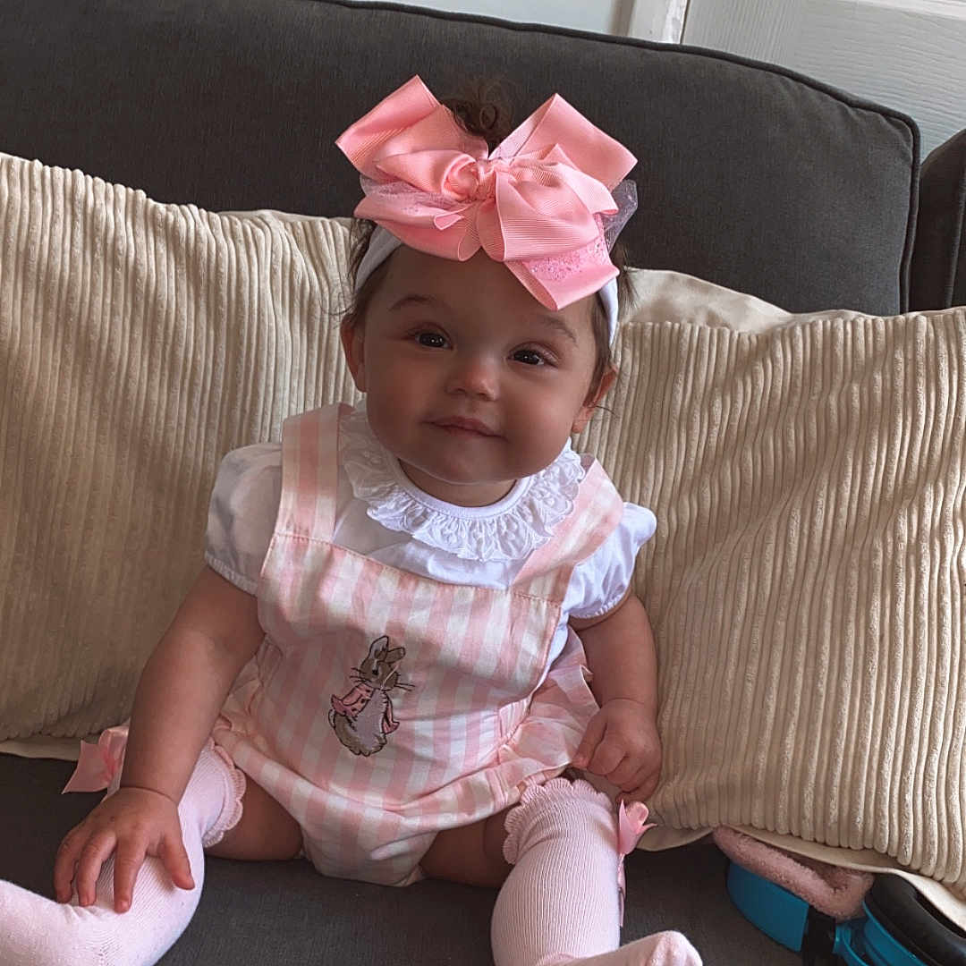 Valensia-Rose joined the competition — help win amazing prizes! baby, child, couch, cozy, cute, furniture, girl, happy, headband, home, indoors, infant, pillows, pink_bow, pink_outfit, portrait, sitting, smiling, sock, white_shirt