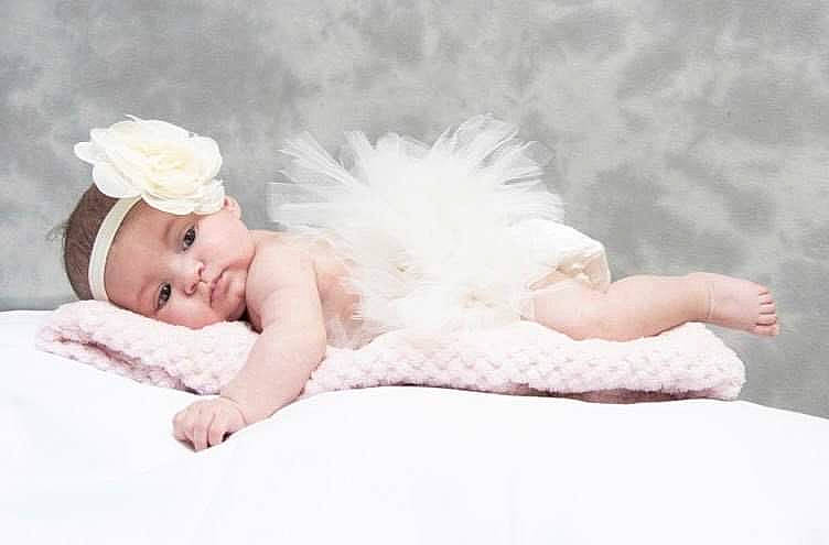 Azelia participe au concours pour gagner de l'argent avec cette photo : baby, baby_toddler_clothing, bedding, bridal_accessory, comfort, dress, eye, fashion_accessory, feather, flash_photography, fur, hair_accessory, happy, hat, headband, headpiece, linens, person, sitting, smile