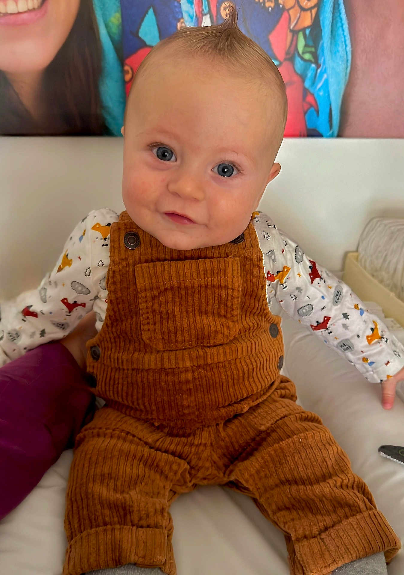 Scott a rejoint le concours — aidez-le/la à gagner de superbes lots ! baby, child, infant, face, blue_eyes, mohawk, overalls, corduroy, shirt, fox_pattern, bed, indoor, portrait, smile, person, cute, curious, colorful_background, adult, hand