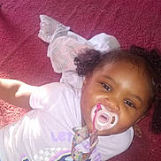 A'Kayda is registered to the contest to win money with this photo: child, toddler, baby, pacifier, pacifier_clip, smile, curly_hair, carpet, purple_shirt, blue_pants, indoor, toy, blanket, playtime, portrait, cute, happy, face, skin, floor