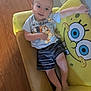 baby, chair, clothing, couch, crib, cushion, face, furniture, head, homedecor, indoors, infantbed, pants, person, photography, pillow, portrait, shorts, sitting, t_shirt