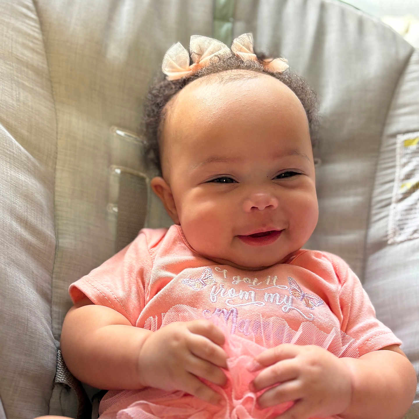 Diamond is registered to the contest to win money with this photo: adorable, apparel, baby, bow, child, closeup, cushion, cute, face, hands, happy, indoor, infant, pink_clothing, portrait, seat, sitting, smiling, soft_lighting, toddler