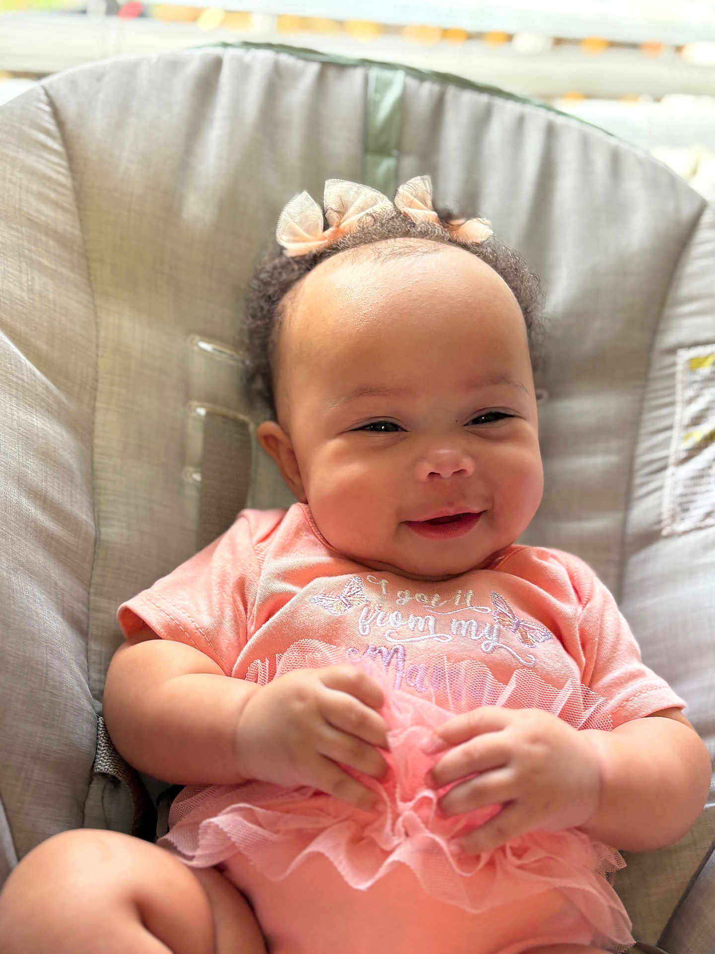 Diamond is registered to the contest to win money with this photo: baby, smiling, infant, pink_clothing, bow, cute, hands, face, cushion, seat, child, portrait, happy, indoor, soft_lighting, closeup, toddler, apparel, sitting, adorable